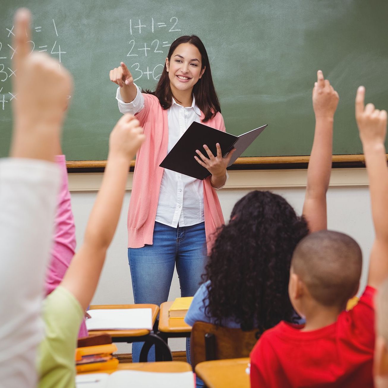 A teacher calling upon eager students to answer a question.