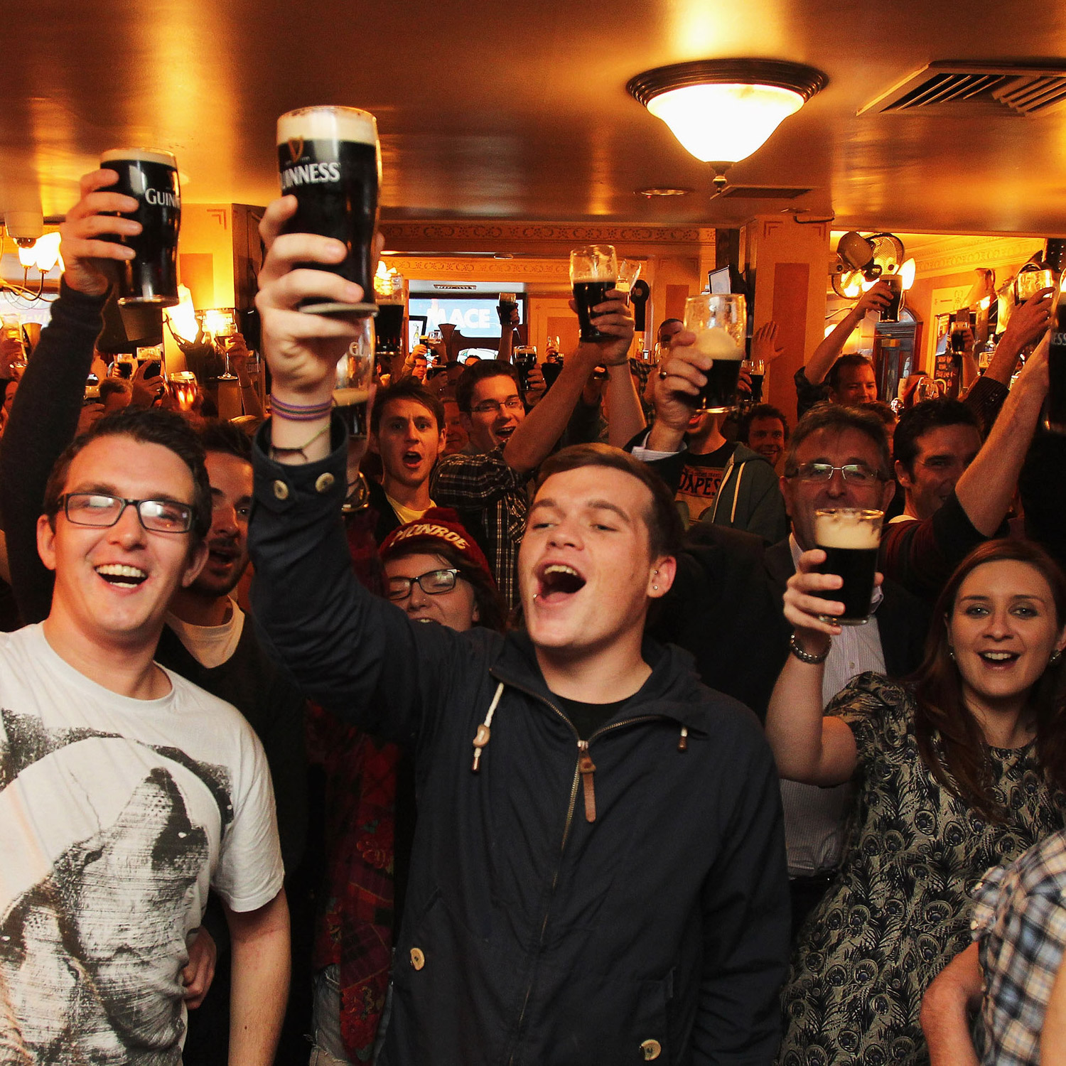 Happy pub patrons raising their glasses in a collective cheers.